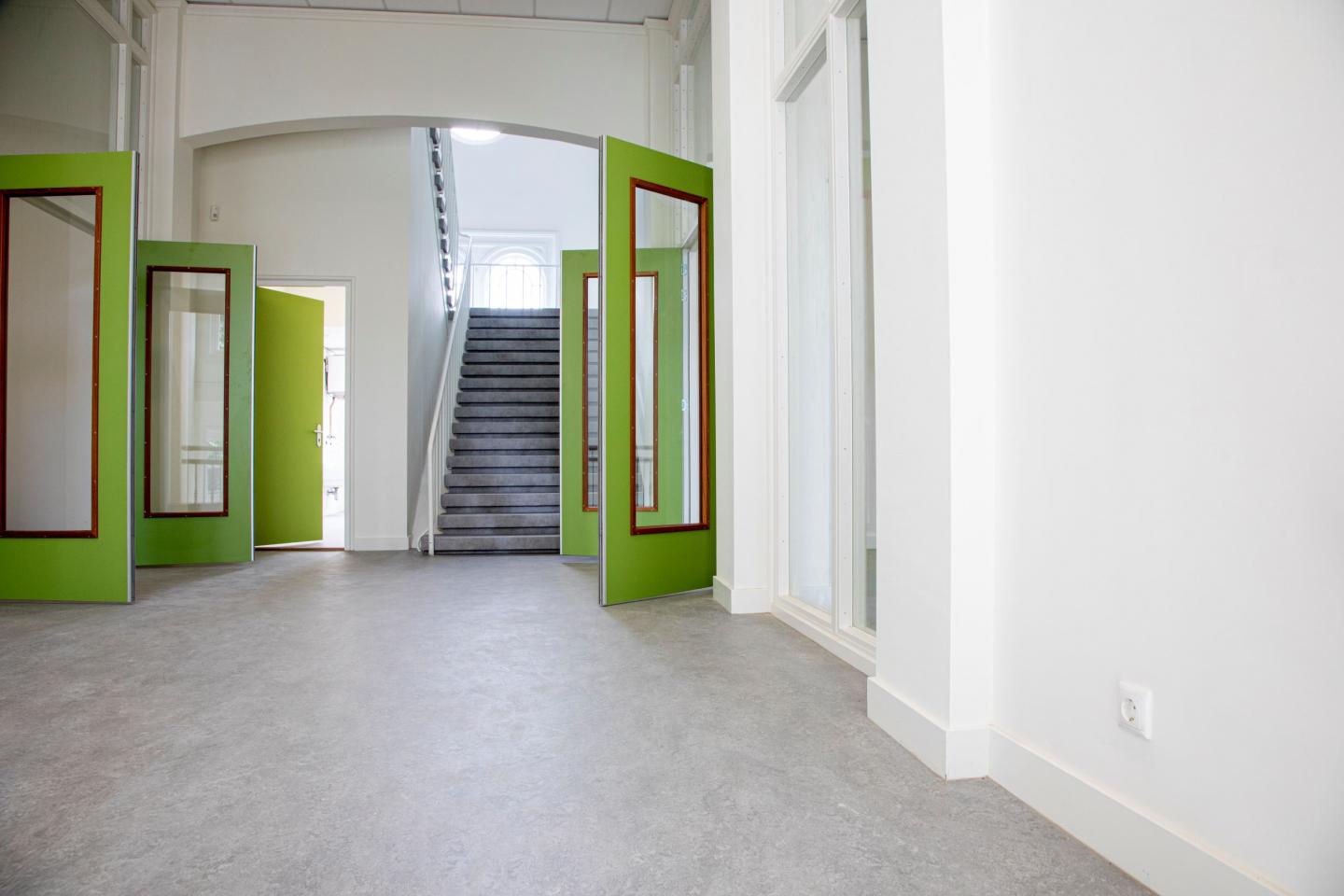 Hal van schoolgebouw met groene deuren die open staan