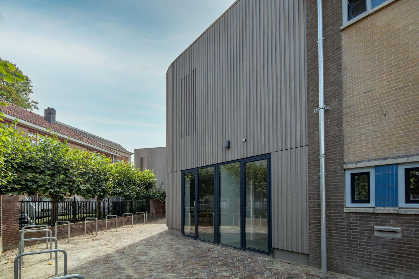 Buitenkant van OBS Oldenije met uitbouw van hout en schoolplein